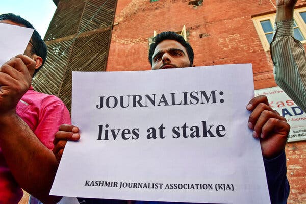 A Kashmiri journalist holds a sign reading “Journalism: lives at stake a protest